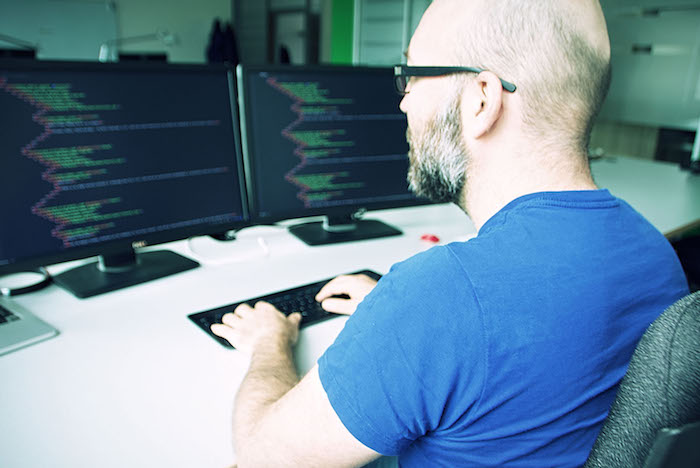 Neos IT Services, Arbeitsumgebung, Mitarbeiter am programmieren vor dem Monitor