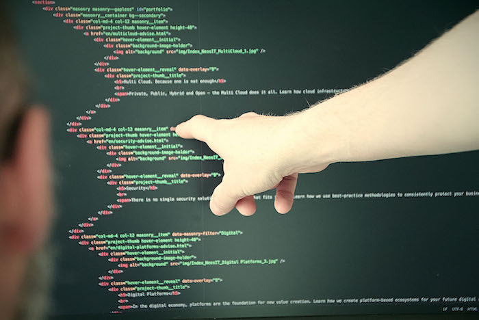 Finger zeigt auf Monitor mit Code